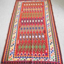 A Persian kilim rug, with coloured geometric designs, on a red ground, 280 x 155cm
