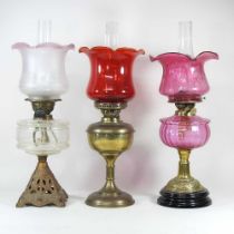 Two early 20th century brass oil lamps, with glass shades, together with another, with shade,