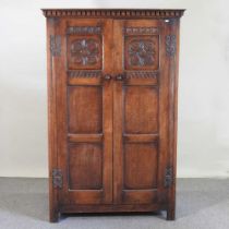 An 18th century style carved oak cupboard, enclosed by a pair of panelled doors 114w x 54d x 176h