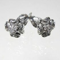 A pair of large 14 carat white gold and diamond earrings, of floral design, with hinged backs,