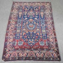 A Persian woollen rug, with floral designs, on a blue ground, 219 x 142cm