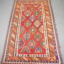 A Persian qashqai kilim, with all over lozenges, on a red ground, 290 x 175cm