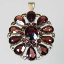 An unmarked two colour filigree garnet pendant, of flowerhead design, set with ten pear shaped