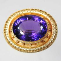 An early 20th century gilt brooch, with a large cushion cut amethyst, set within an ornate gilt