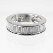 A modern 18 carat white gold and diamond half hoop eternity ring, channel set with a row of baguette