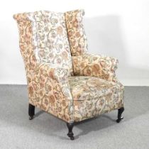 A Georgian style floral upholstered wing armchair, on turned legs