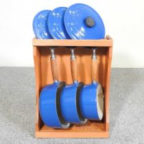 A set of three graduated Le Creuset saucepans, in a wooden stand, 31cm wide (4) Overall condition is