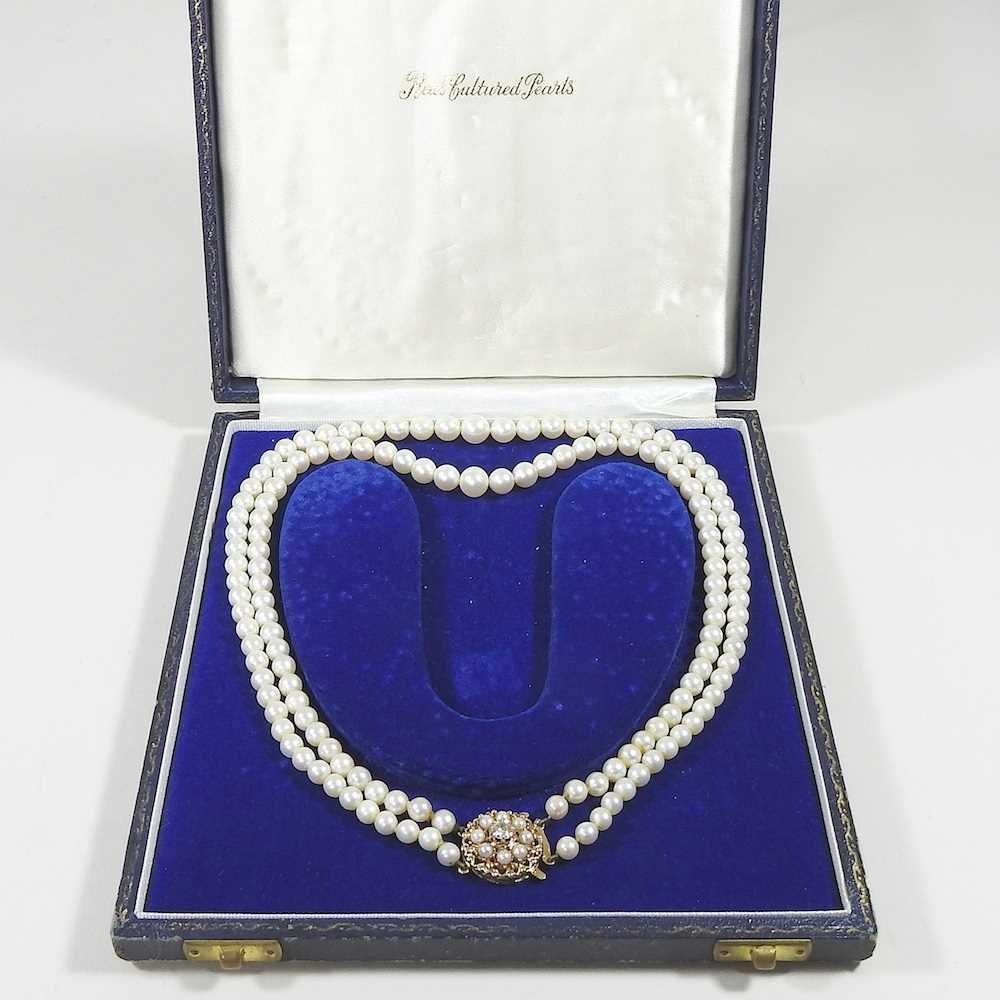 A double strand cultured pearl necklace, with an ornate 9 carat gold clasp set with a central