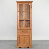 An antique pine narrow cabinet, with a glazed upper section 61w x 40d x 170h cm