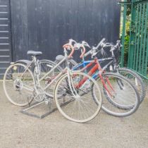 A ladies vintage Raleigh bicycle, with two others and a bike stand