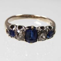 A sapphire and diamond ring, set with a row of graduated alternating stones, marked indistinctly,