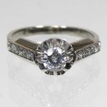 An unmarked diamond cluster ring, approximately 0.2 carat illusion set, with diamond shoulders, 3.