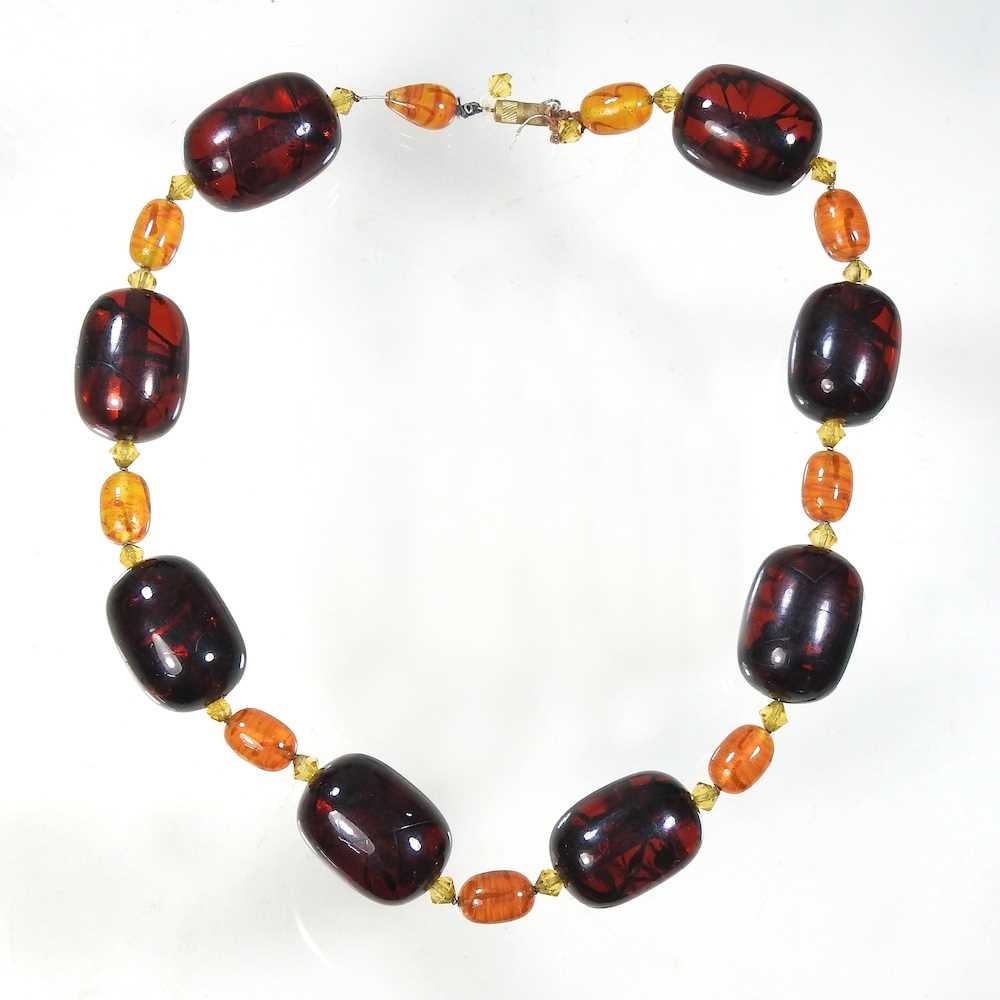 A large two colour amber bead necklace, set with alternating oval beads, 42cm long Largest beads 3cm