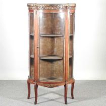An early 20th century French marble top vitrine, of serpentine shape, with a pierced brass gallery