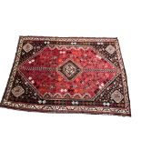 A Persian style rug on red ground the central floral medallion surrounded by bird and floral fillers