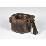 An antique wooden mortar with bronze pestle the mortar 7½in. (19cm.) at widest.* Condition: Mortar