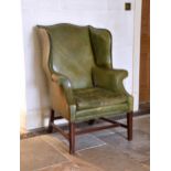 A Georgian style green leather wingback armchair late 20th century, with mahogany tapered front legs