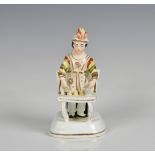 A 19th century Staffordshire porcelaneous figure of a Magician c.1830, the conjuror wearing a