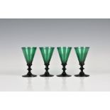 A set of four late-George III green wine glasses the funnel bowls on a bladed knop stem and plain