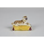 An 18th century English porcelain figure of a pug dog on a cushion possibly by Bow, modelled