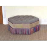 A large hexagonal pouffé or stool with buttoned seat and tasseled fringe, on castors, 37½in. (95.