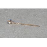 An Edwardian rose gold, sapphire and pearl stick pin.