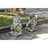 A pair of antique carved limestone seated heraldic lions with weathered patina, each holding a
