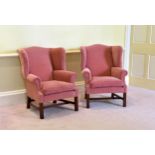 A pair of George III style wingback arm chairs late 20th century, raised on square, moulded front