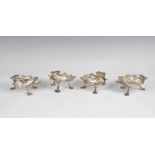 A closely matched set of four George II and later silver shell salts three with rubbed London marks,