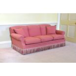 A Howard style three seater sofa late 20th century, in gold piped deep pink upholstery, with fringed