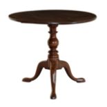 A George III circular mahogany tilt-top tripod table with a baluster turned column on swept supports