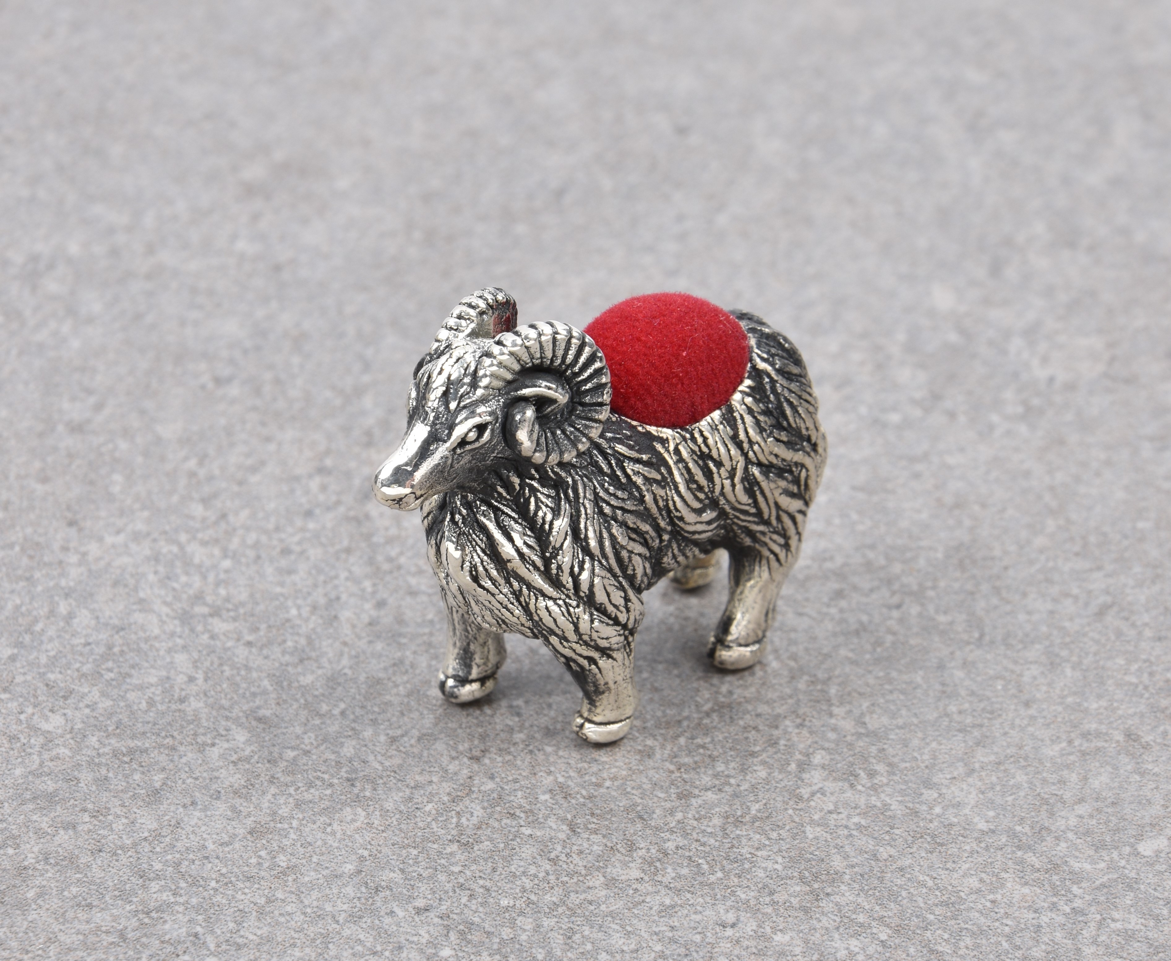 A novelty silver ram pin cushion, modern, marked 'Sterling', with dark red felt cushion, 4.1cm.