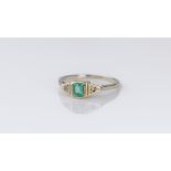 An Art Deco 9ct white gold, hiddenite and diamond three stone ring, the rub-over set emerald cut