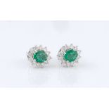 A pair of 18ct white gold, emerald and diamond cluster earrings, the two oval cut emeralds, total