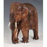 A large Indian carved hardwood figure of a caparisoned elephant, mid-20th century, 15in. (38cm.)