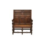 A good early 18th century oak settle, the stepped top rail over a panelled back with box and ebony