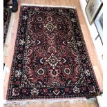A Persian style rug, on red ground with floral medallions and fillers, flanked by carnation and