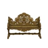 An Italian early 19th century carved limewood bench with a shaped high back, conjoined by a floral