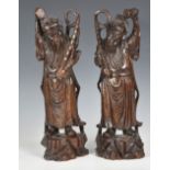 A pair of Chinese carved hardwood figures of immortals, probably late 19th / early 20th century, the