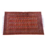 A 20th century Bokhara style rug, the brick red ground with three rows of fifteen Guls, within