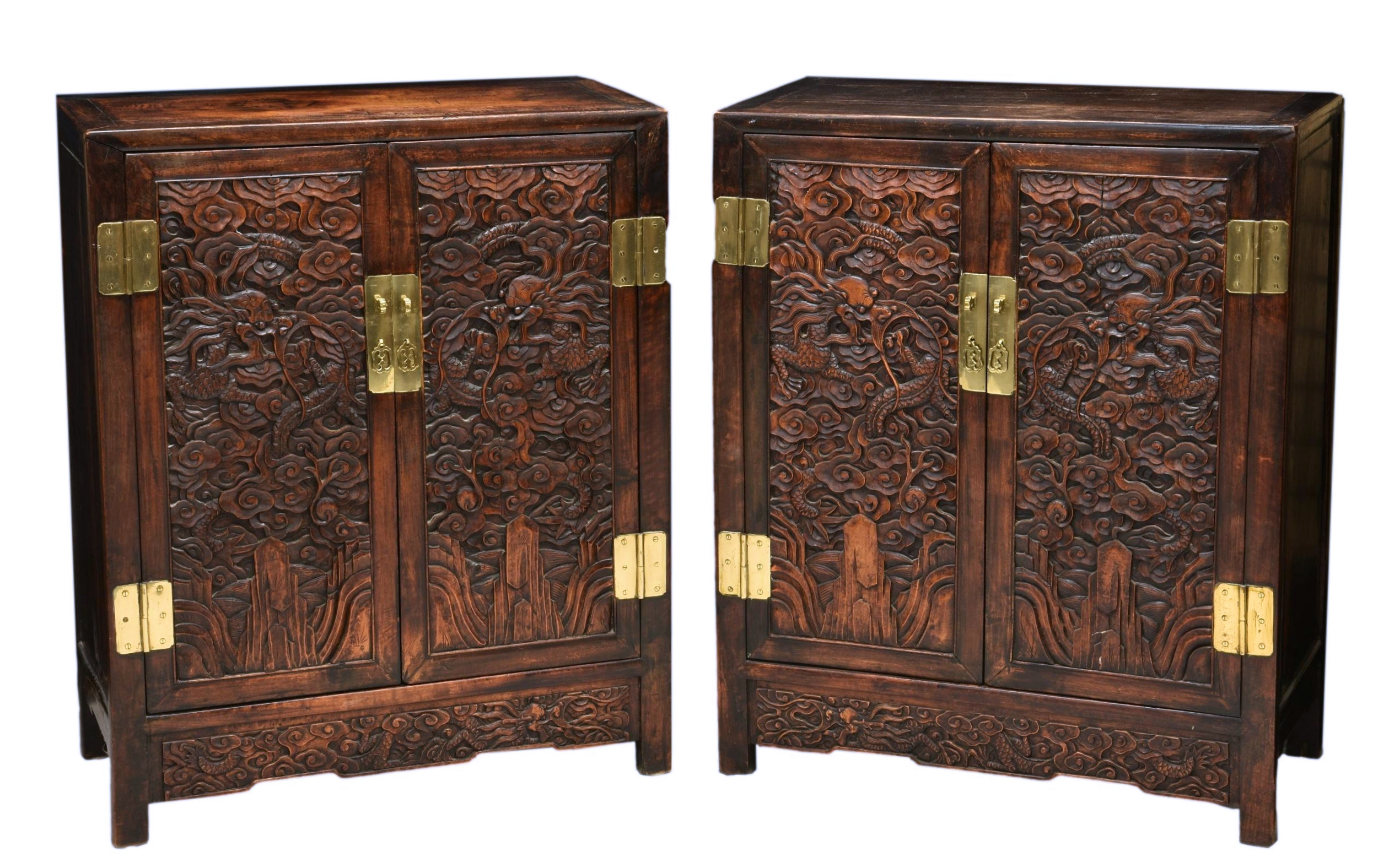 A pair of Chinese carved hardwood cabinets, the plain rectangular top over two cupboard doors with a
