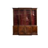 A mid-19th century mahogany breakfront cupboard bookcase, the flared cornice over four astragal