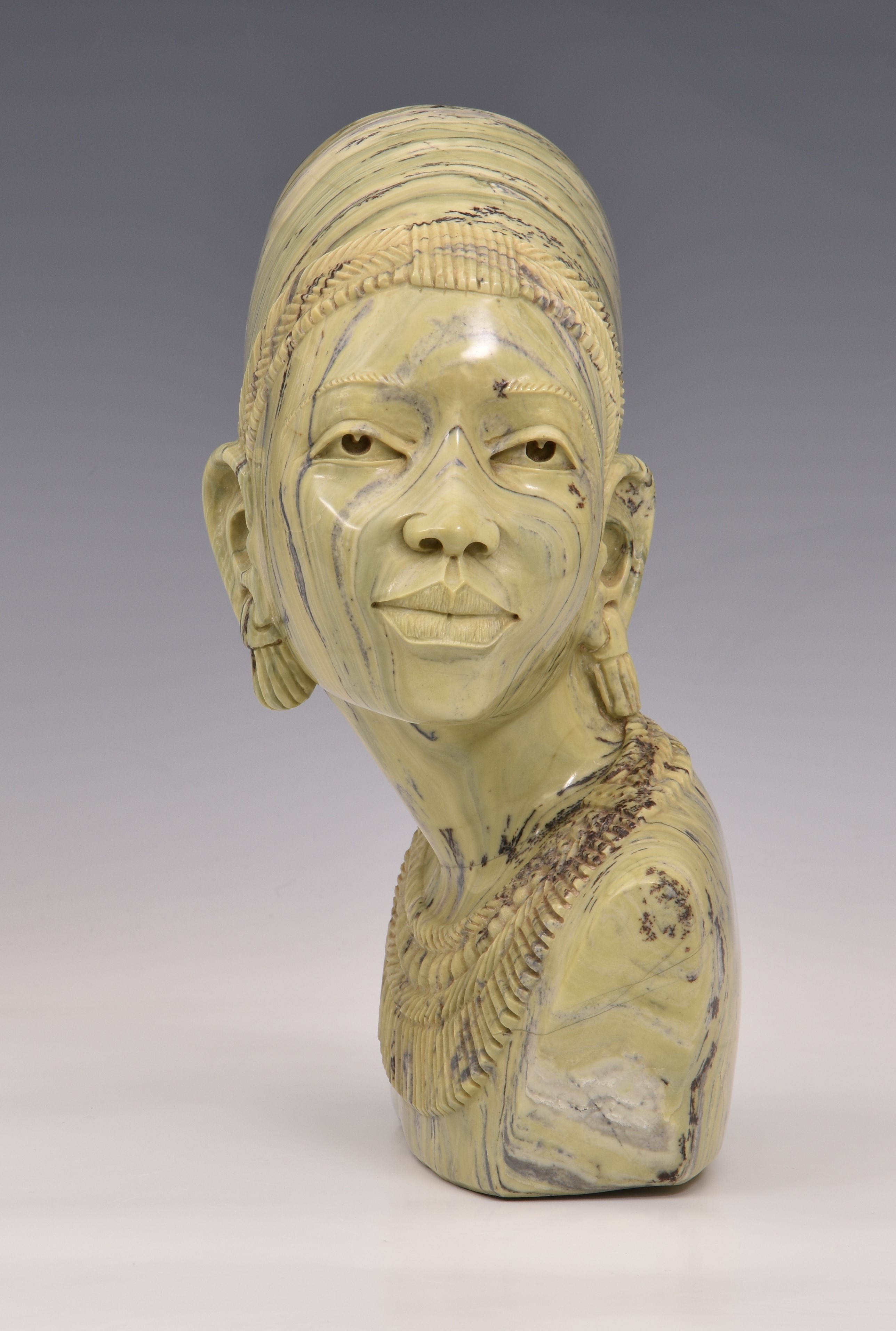 A carved greenstone bust of a young African woman, unsigned, late 20th century, 11¼in. (28.5cm.) - Image 2 of 3