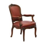 A Victorian carved walnut and red leather showframe open armchair, the floral and scroll carved
