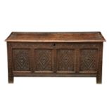 A late 17th century four panel oak coffer, the two plank top with a carved border opening to a