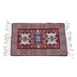 A small 20th century wool rug, with three geometric medallions and repeat filler motifs on red