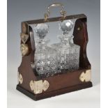 A two bottle lockable tantalus, holding square cut glass decanters, 9½in. (24.2cm.) wide. (no key)