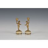 A pair of gilt metal and onyx figural putti / cherub candlesticks by Halcyon Days, One holding urn