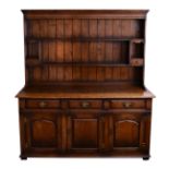 A George III style oak dresser, late 20th century, the moulded cornice over an enclosed plate rack