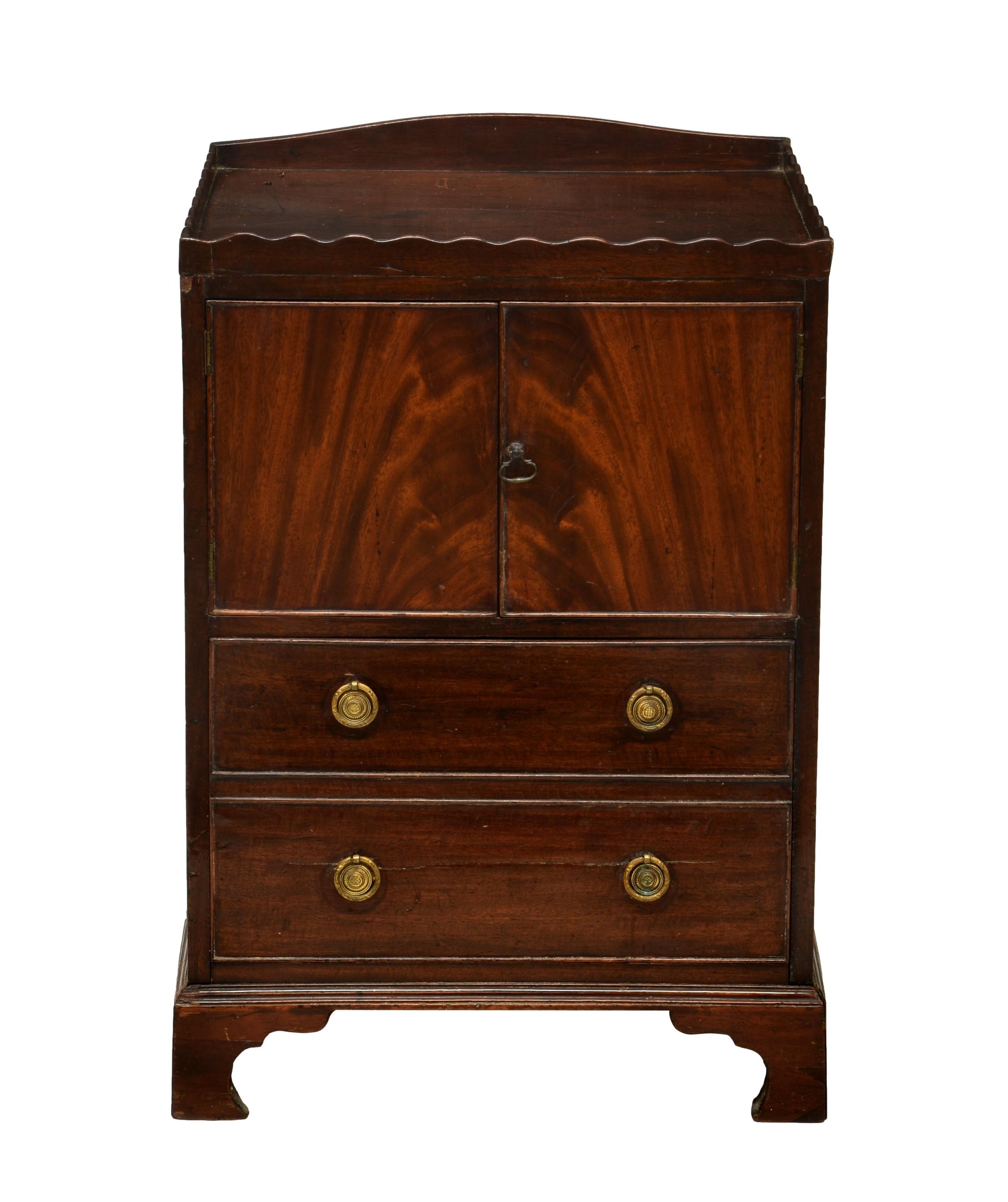 A George III mahogany bedside night table cabinet, the tray top with wavy gallery, over a two-door